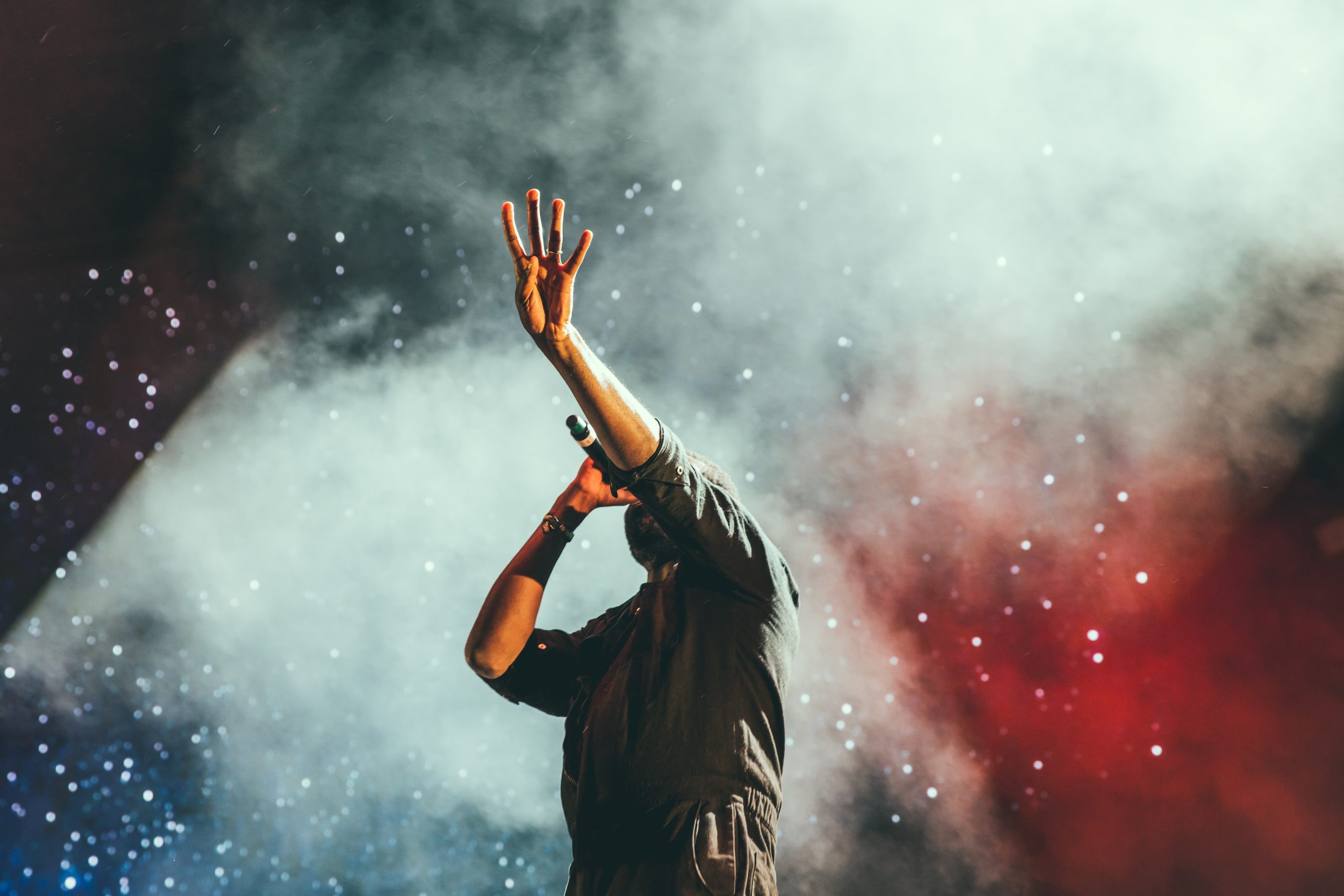 Musician singing into a microphone with his hand in the air